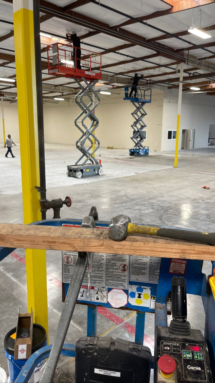 Crew on scissor lifts installing sprinkler piping in the Fremont warehouse